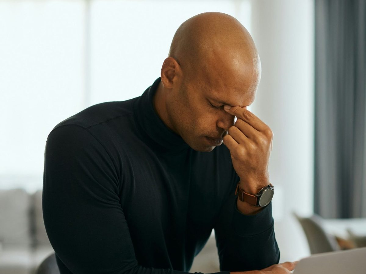 Man rubbing the bridge of his nose at a laptop with eye strain and a headache — assessment and management of common eye conditions with Dr. Roxanna Gangi, Optometrist in York Region