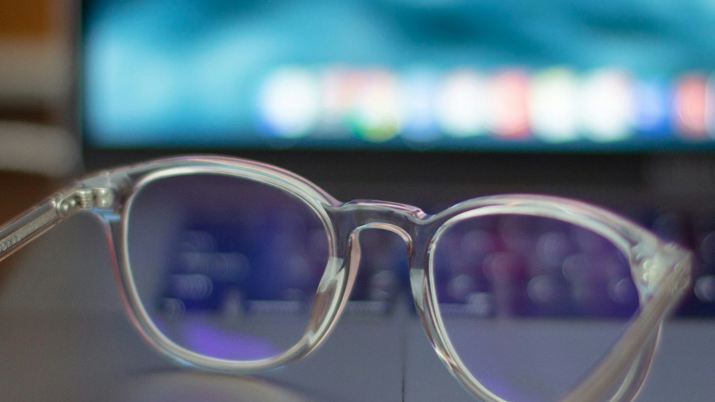 Clear-frame computer glasses resting on a laptop keyboard in front of a glowing screen — blue light and digital eye strain relief alongside presbyopia solutions with Dr. Roxanna Gangi at Pro Eye Exam in York Region